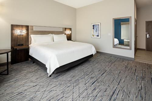 棕榈荒漠Holiday Inn Express & Suites Palm Desert - Millennium, an IHG Hotel的配有一张大床和镜子的酒店客房