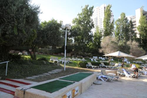 耶路撒冷Jerusalem Hotel Private Luxury Suites near Western Wall的公园配有躺椅、遮阳伞和桌子