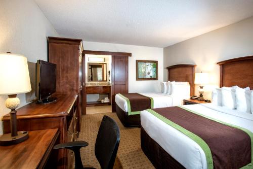奥兰多Rosen Inn Lake Buena Vista的酒店客房设有两张床、一张桌子和一台电视。