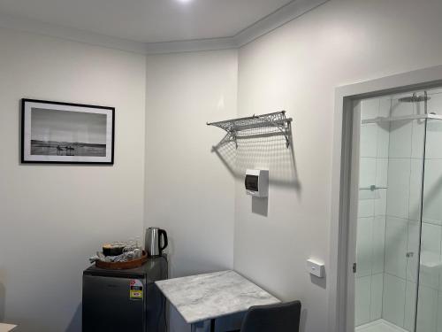 本迪戈BENDIGO BOTANIC MOTEL- with KING BEDS-REFURBISHED 2022的带淋浴、桌子和玻璃门的浴室