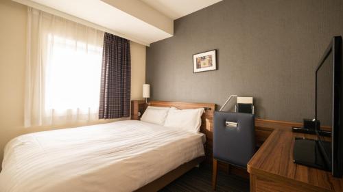 东京Via Inn Shinagawa Oimachi的一间卧室配有一张床、一台电视和一个窗口