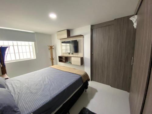 麦德林Conquistadores Romantic, Medellín的一间卧室配有一张床、一个橱柜和一台电视