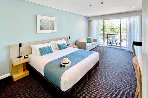 悉尼库吉金沙大酒店和公寓的一间卧室配有一张大床,上面有帽子