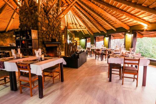 奥马鲁鲁Ondudu Safari Lodge的一间带桌椅和壁炉的用餐室