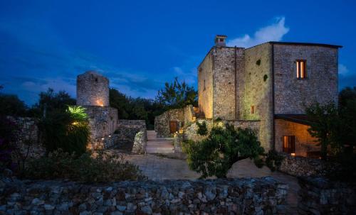 孔韦尔萨诺Masseria Montepaolo Dimora di Charme的一座古老的石头建筑,晚上有两座塔楼