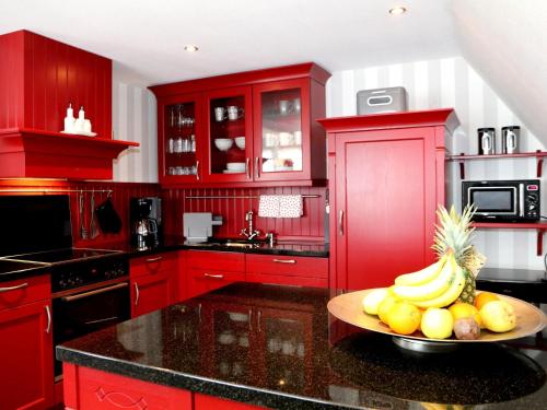 奥尔珀Ferienwohnungen Schimsheimer Rhode的红色的厨房,在柜台上放一碗水果