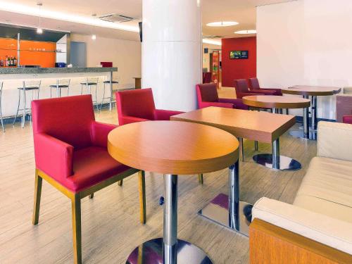 莫索罗Ibis Mossoro的一间设有桌子和红色椅子的等候室