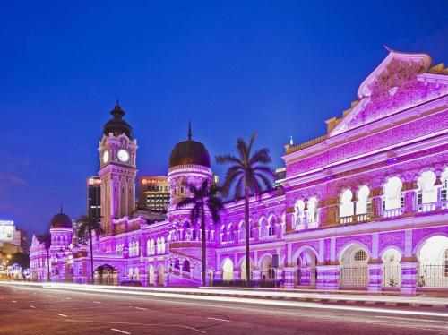 吉隆坡Swiss Hotel Kuala Lumpur的一座用钟楼点亮紫色的建筑
