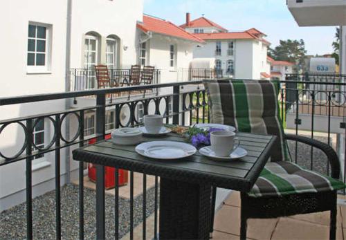 巴贝Haus Meeresblick - Ferienwohnung Strandidyll A 1.16 (Ref. 128659 u2)的阳台上的桌子,带两个杯子和椅子