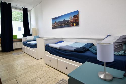 科隆Boardinghouse in Cologne *free WiFi*的一间卧室配有两张床和一张带台灯的桌子