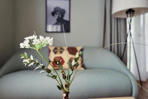 穆尔海姆Biohotel Alte Post的长沙发旁边的一张桌子上装有白色花朵的花瓶