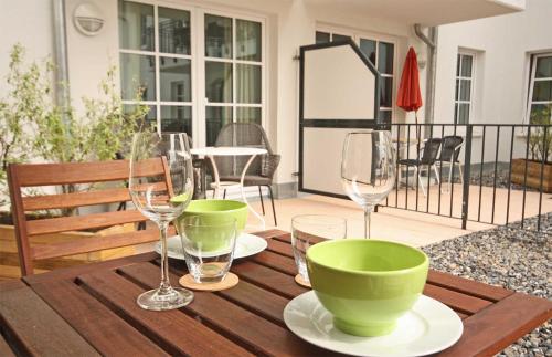 巴贝Haus Meeresblick - Ferienwohnung Strandnah A 1.07 (Ref. 128675)的一张木桌,配有两个绿色碗和酒杯