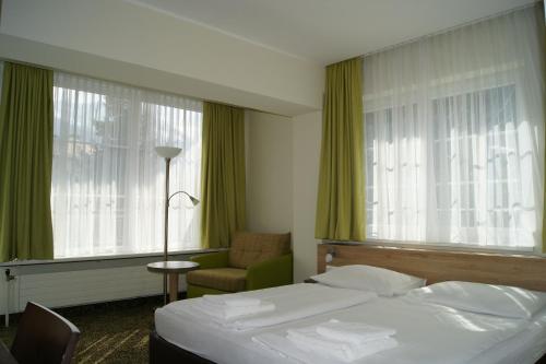 巴德加斯坦Hotel Lindenhof的一间卧室配有一张床、一把椅子和窗户。
