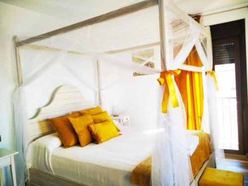 VillamielEscapada Romantica con Bañera y vistas al Castillo de Trevejo的卧室配有白色天蓬床和黄色枕头