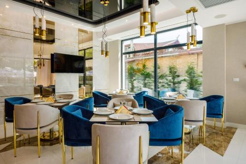 马马亚Onal Boutique Hotelier的餐厅设有蓝色的桌椅和大窗户