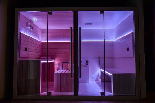 斯特雷萨Sempione Boutique Hotel的一间设有玻璃门和紫色灯的房间