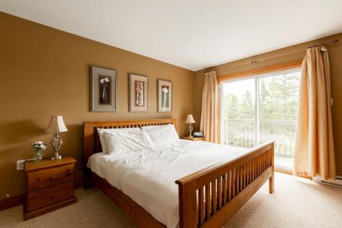 蒙特朗布朗Serenity Peaks Lodge by InstantSuites-LaBete Golf的一间卧室设有一张大床和一个窗户。