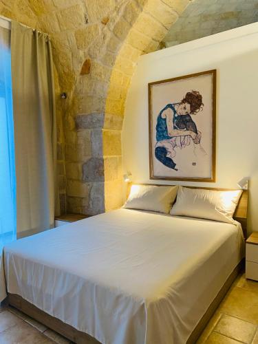 特拉尼La prima dimora - Suite的卧室配有一张白色床,墙上挂有绘画作品