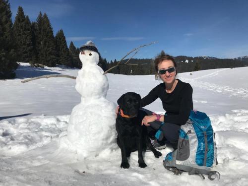 佩尔吉内瓦尔苏加纳CastelCharme b&b的雪人旁边的女人和狗