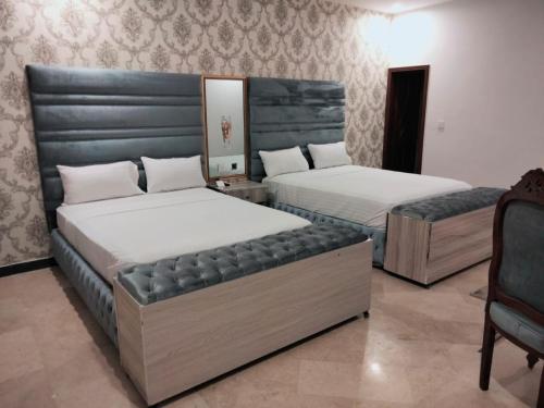 拉合尔Grand Swiss Hotel&Apartment Lahore的一间卧室配有两张床和椅子