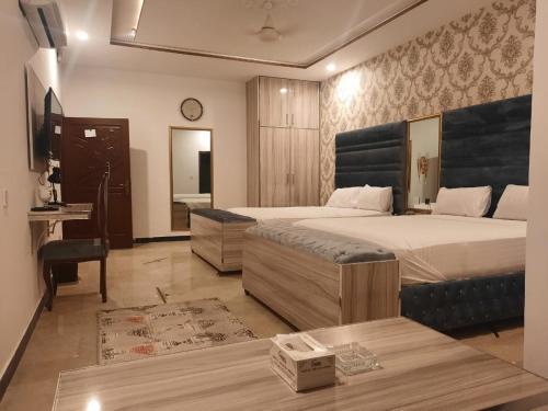 拉合尔Grand Swiss Hotel&Apartment Lahore的一间卧室配有两张床、一张桌子和一面镜子
