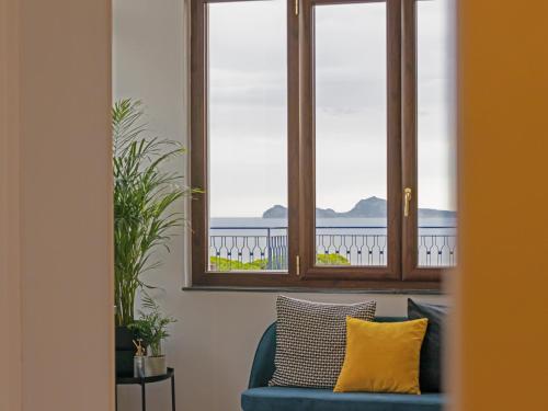 埃尔科拉诺Panorama Love to Stay的窗户间里一张蓝色的沙发,上面有黄色的枕头