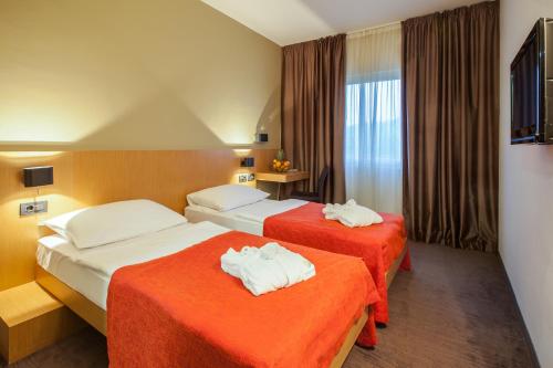 图赫尔斯克利普利采图和乐街特美好酒店的酒店客房带两张带橙色床单的床