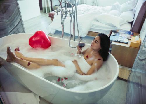 博卡拉Hotel Annapurna View Sarangkot的躺在浴缸里的女人,喝一杯葡萄酒