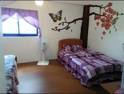 Lanyu兰屿我家の民宿的卧室配有一张床铺,墙上挂着一棵树和蝴蝶