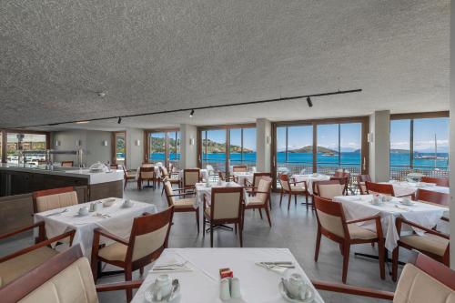 斯基亚索斯镇Alkyon的餐厅设有白色的桌椅和窗户。