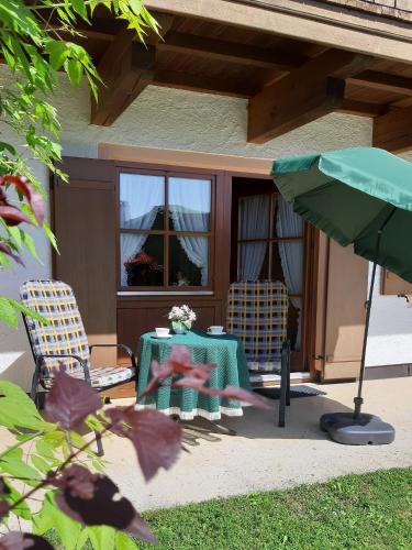 雷特温克尔Ferienwohnung Lübbers的庭院配有两把椅子、一张桌子和一把遮阳伞