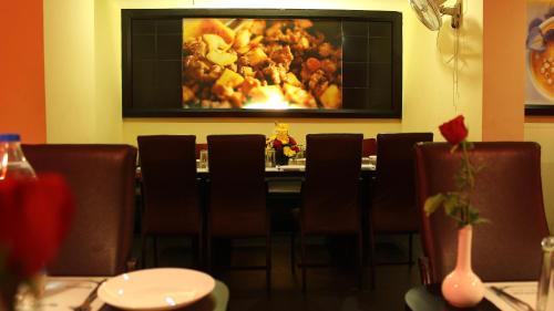 钦奈清奈之门酒店的餐厅配有桌椅和墙上的绘画作品