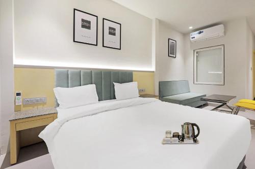 博帕尔FabHotel Oasis Yellow Courtyard的卧室配有一张白色大床和一把椅子