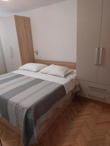 拉布Apartments Mlacovic的一间卧室配有床和白色橱柜