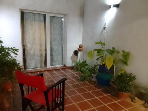 坦迪尔Departamentos R y R Azcuénaga的一间红色椅子、植物和窗户的房间
