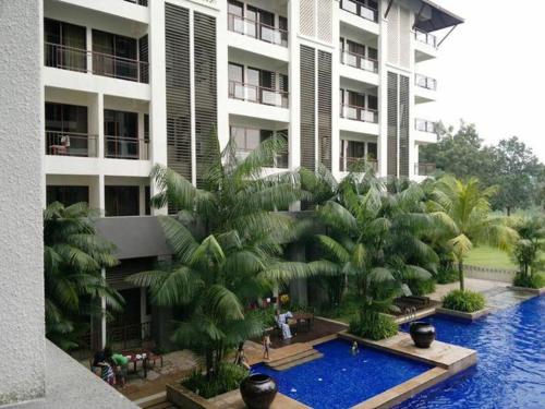 士姑来Garden View Pulai Springs Resort的一座带游泳池和棕榈树的大型建筑