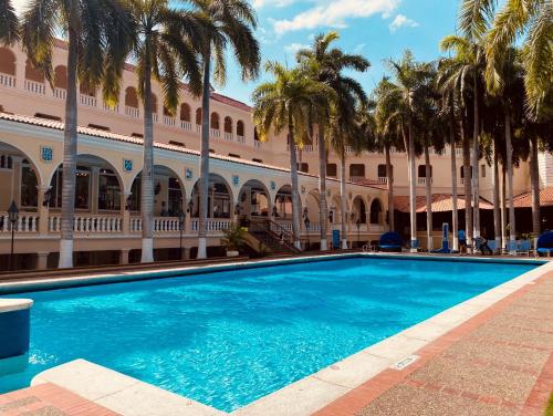 巴兰基亚草原酒店的棕榈树建筑前的游泳池
