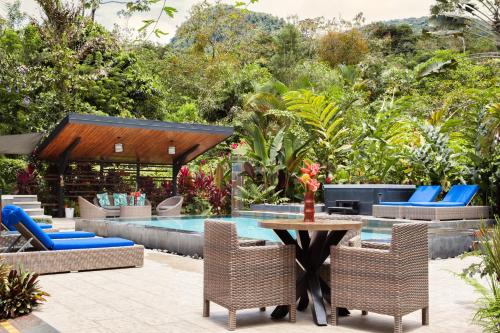 福尔图纳Tifakara Boutique Hotel & Birding Oasis的一个带椅子和桌子的庭院,毗邻一个游泳池