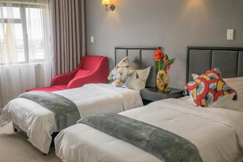 SandtonAtlantic Pearl Guest House Broadacres的酒店客房,设有两张床和一张红色椅子
