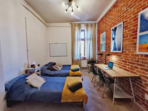 奥尔什丁Smart Hostel Olsztyn的一间卧室设有两张床、一张桌子和砖墙
