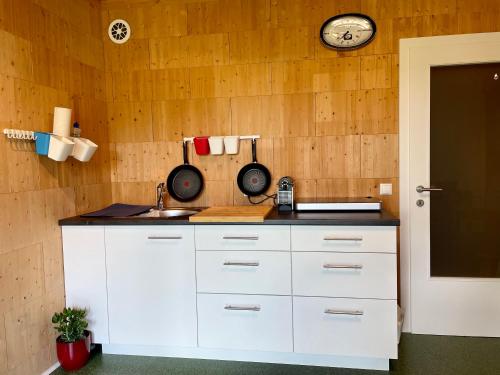 施奥弗灵Ferien in Holz - Fühle die Gemütlichkeit Enjoy的厨房配有白色橱柜和墙上的时钟