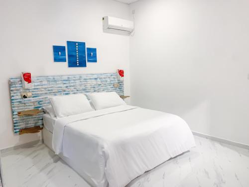 拉斯杜Fins Dive and Leisure Hotel的白色卧室设有白色的床和蓝色的墙壁