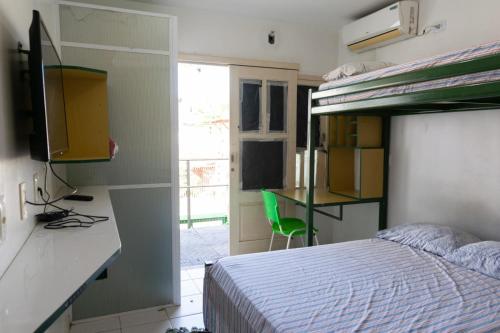特雷西纳FLAT ACONCHEGANTE的一间卧室配有一张床和一张带绿椅的书桌