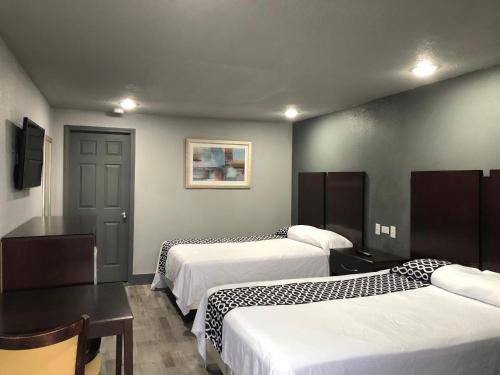 尼斯维尔Budget Inn Valparaiso/Niceville @ Eglin AFB & Destin-FWB Airport的酒店客房带两张床和一张桌子以及椅子。