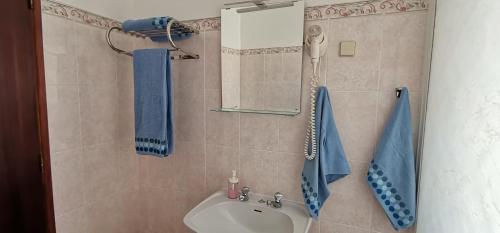 科武港Apartamentos Guiomar Campos的浴室设有水槽、镜子和蓝色毛巾