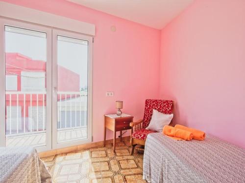 Mareny BarraquetasCASA EN LA PLAYA VALENCIA EL PERELLO的卧室设有粉红色的墙壁、椅子和窗户