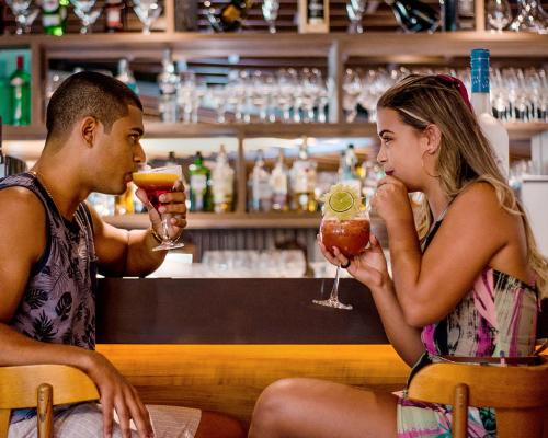 卡波布里奥帕拉迪索公司酒店的坐在酒吧喝饮料的男人和女人