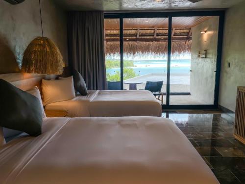 巴卡拉尔Hotel Amainah Bacalar Adults Only的酒店客房设有两张床,享有海景。