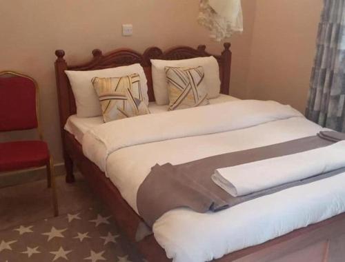 基塔莱Stay.Plus Villa Serene Kitale的一间卧室配有一张大床和红色椅子