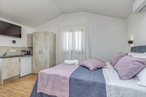 波雷奇Rooms Nilda的一间卧室配有一张带紫色枕头的大床